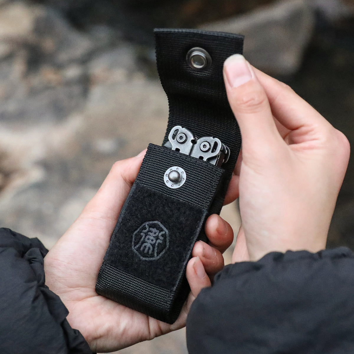 OP-01 MOLLE multitool sheath holding a folding multi-tool with embossed metal buckle